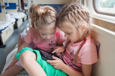 47603958 - two girls playing in the second-class tablet in a train