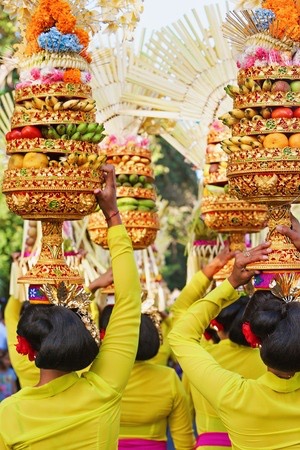 44226616 - procession of beautiful balinese women in traditional costumes carry ritual offerings on heads for hindu ceremony. arts festival, culture of bali people, and indonesia islands. asian travel background
