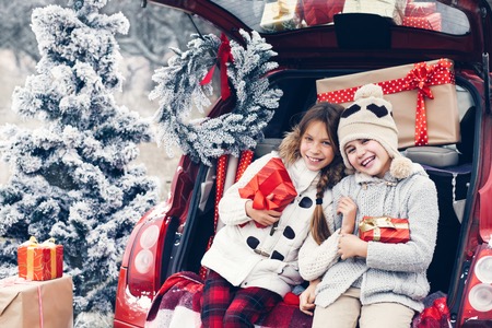 47035438 - holiday preparations. pre teen children enjoy many christmas presents in car trunk. cold winter, snow weather.